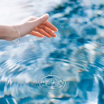 Calm water surface of a swimming pool reflecting the clear sky.